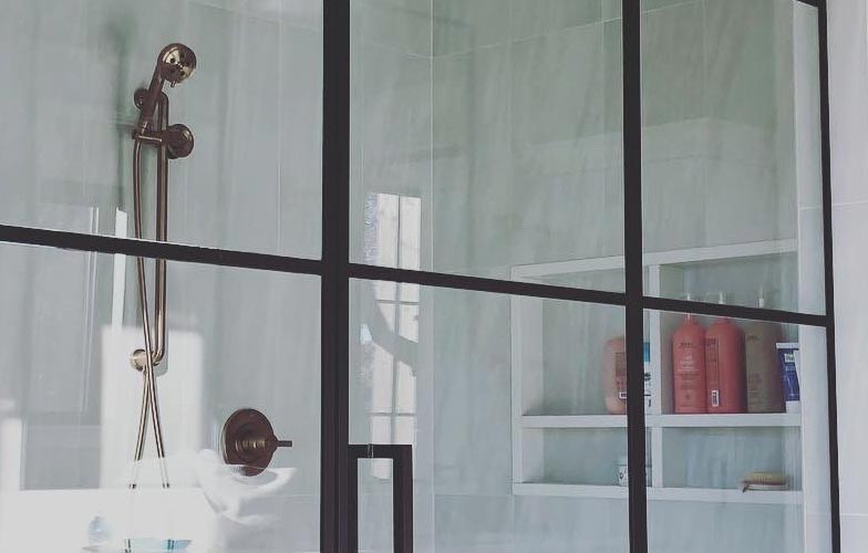 a framed shower enclosure with seat and shelf