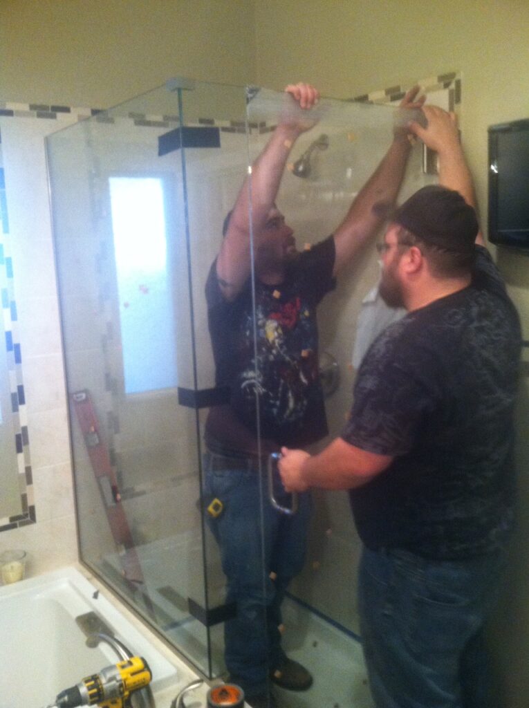 Matt and Doug setting the door in place, getting ready to anchor the hinges to the wall for this 3-panel shower enclosure in aurora colorado